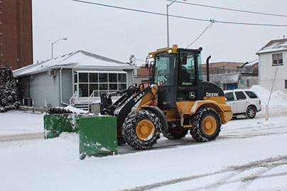 Yellow John Deere Tractor moving Snow on the Street